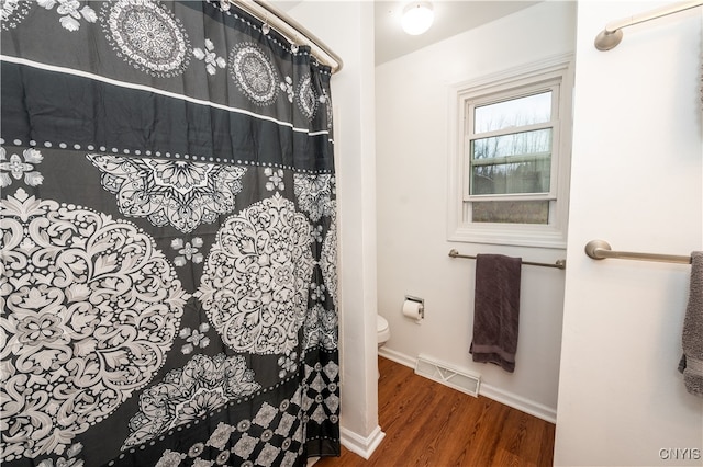 bathroom with hardwood / wood-style floors, toilet, and a shower with curtain