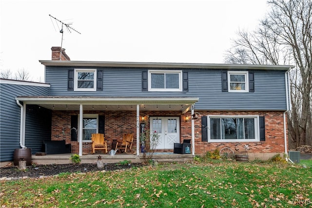 view of front property featuring a front yard, a porch, and central AC unit