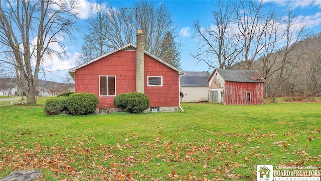 view of side of property featuring a lawn and an outbuilding