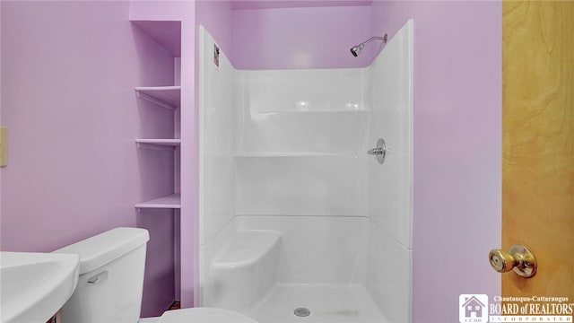 bathroom featuring a shower and toilet