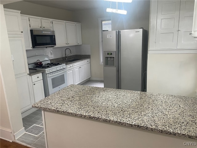 kitchen featuring white cabinetry, stainless steel appliances, pendant lighting, and light stone countertops