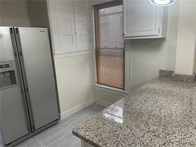 kitchen featuring white cabinetry, stainless steel refrigerator with ice dispenser, and light stone countertops