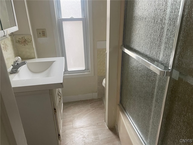 full bathroom with toilet, vanity, and enclosed tub / shower combo