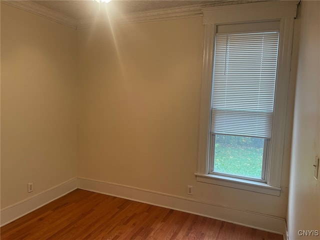 empty room with hardwood / wood-style flooring and ornamental molding