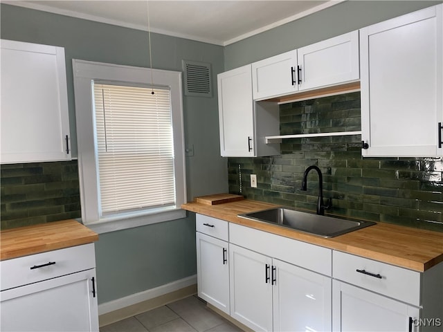 kitchen with wooden counters, backsplash, white cabinetry, and sink