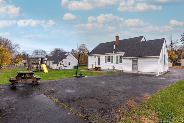 rear view of house featuring a playground and a lawn