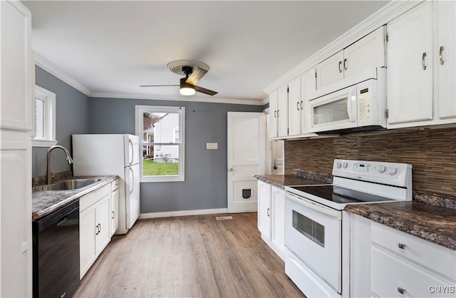 kitchen featuring sink, white cabinetry, light wood-type flooring, white appliances, and dark stone countertops