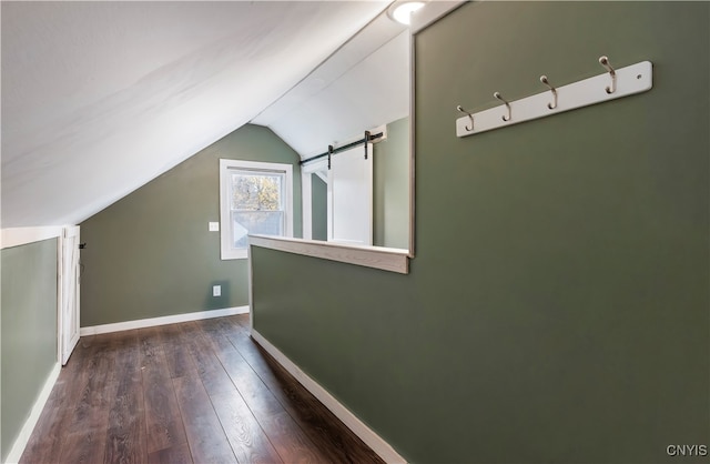 bonus room featuring a barn door, vaulted ceiling, and dark hardwood / wood-style flooring