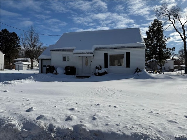 snow covered back of property featuring a garage