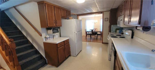 kitchen featuring white appliances, a chandelier, sink, and decorative light fixtures