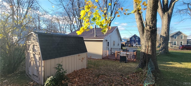 view of property exterior featuring a deck, a yard, and a storage shed