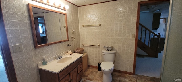 bathroom featuring toilet, vanity, and tile walls