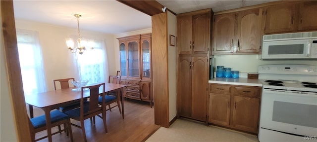 kitchen with white appliances, pendant lighting, light hardwood / wood-style floors, and a notable chandelier