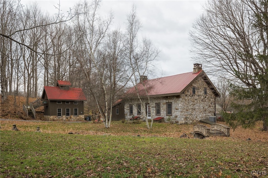 rear view of house with central AC unit and a yard