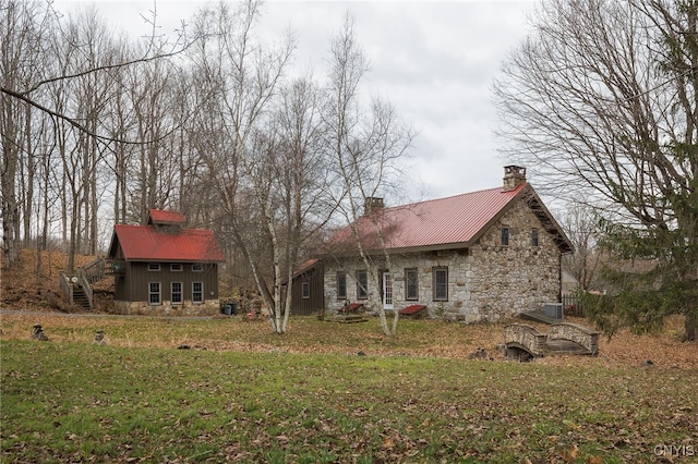 rear view of house with central AC unit and a yard