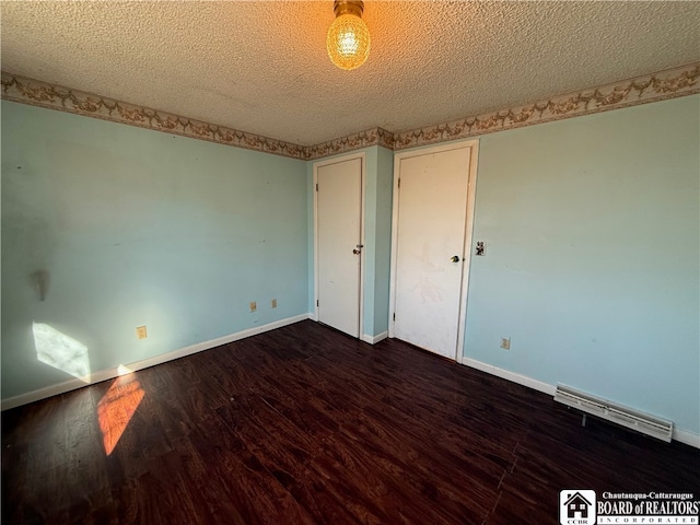 unfurnished room with dark wood-type flooring and a textured ceiling