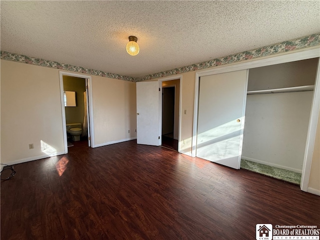 unfurnished bedroom with a textured ceiling, ensuite bath, dark hardwood / wood-style floors, and a closet