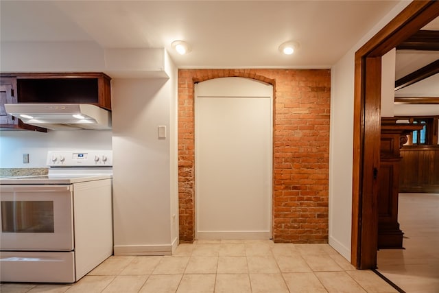 kitchen featuring brick wall, light tile patterned floors, and white electric range oven