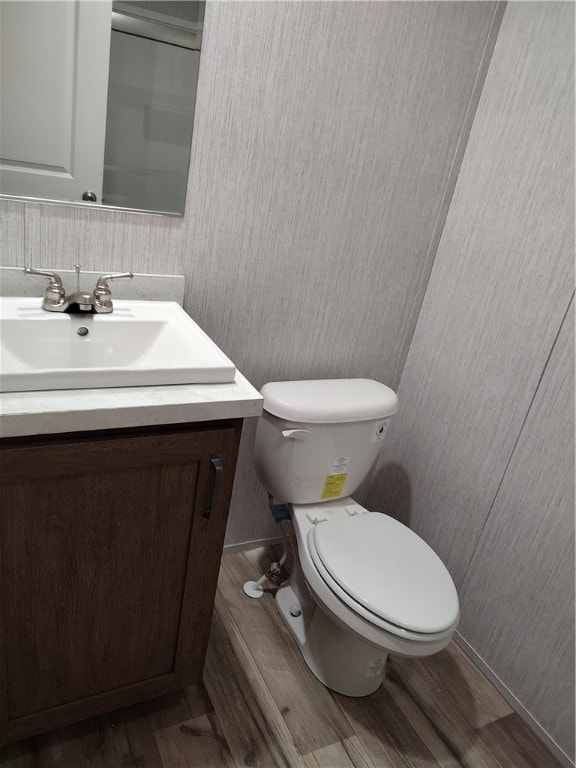 bathroom featuring toilet, vanity, and hardwood / wood-style flooring