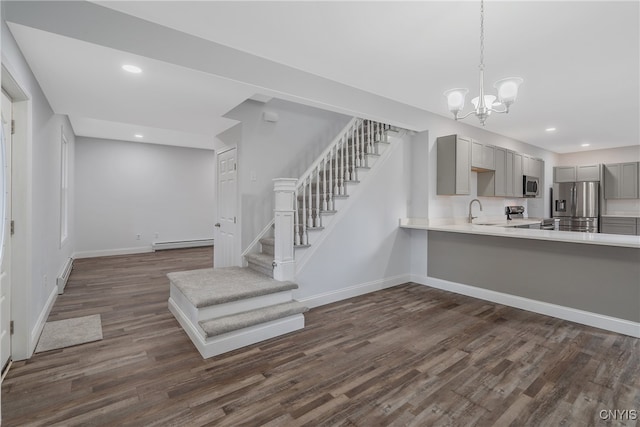 stairs with hardwood / wood-style flooring, a baseboard radiator, sink, and an inviting chandelier