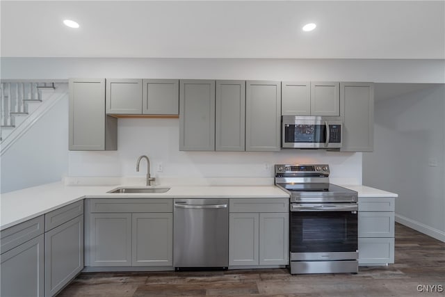 kitchen with gray cabinets, appliances with stainless steel finishes, sink, and dark hardwood / wood-style flooring