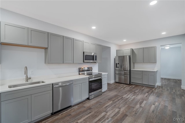 kitchen with appliances with stainless steel finishes, sink, dark hardwood / wood-style floors, and gray cabinetry