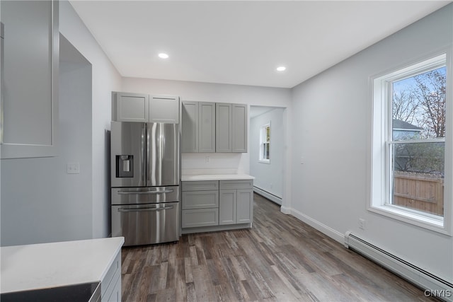 kitchen with stainless steel refrigerator with ice dispenser, dark hardwood / wood-style flooring, a baseboard heating unit, and gray cabinets