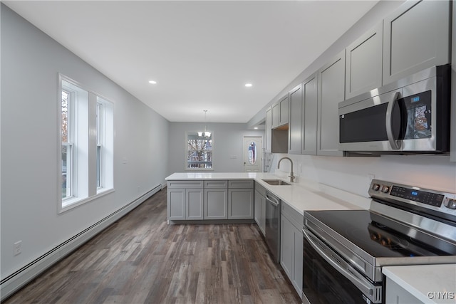 kitchen featuring stainless steel appliances, baseboard heating, plenty of natural light, and decorative light fixtures