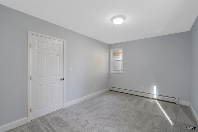 spare room featuring a baseboard radiator and light colored carpet