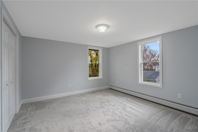 carpeted spare room with a baseboard heating unit