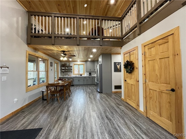 interior space with a towering ceiling, dark hardwood / wood-style floors, wood ceiling, sink, and ceiling fan