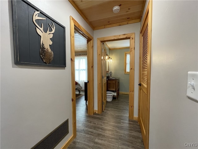 hall featuring dark wood-type flooring, crown molding, and wooden ceiling