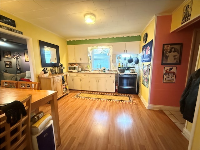 kitchen with white cabinetry, light hardwood / wood-style floors, stove, and crown molding