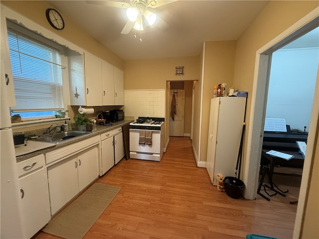 kitchen with light hardwood / wood-style floors, sink, tasteful backsplash, white appliances, and white cabinets