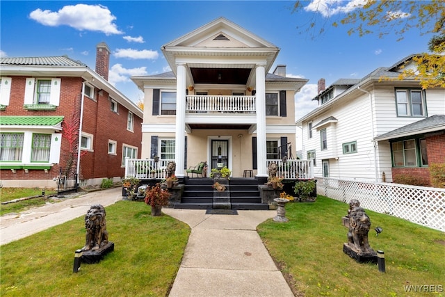 neoclassical home featuring a porch, a balcony, and a front yard