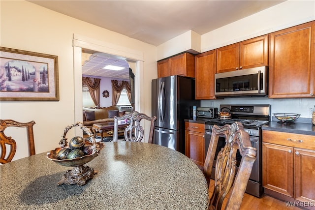 kitchen featuring dark stone countertops, stainless steel appliances, and light hardwood / wood-style flooring