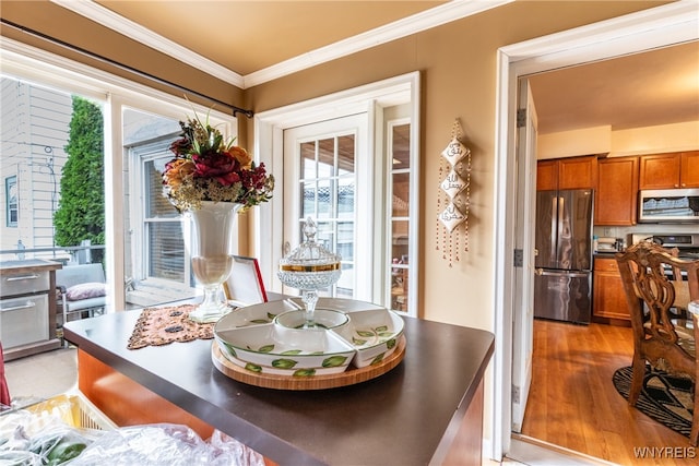 dining area featuring light wood-type flooring and ornamental molding