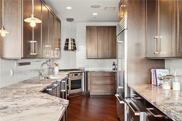 kitchen featuring sink, light stone counters, hanging light fixtures, high quality appliances, and dark hardwood / wood-style flooring