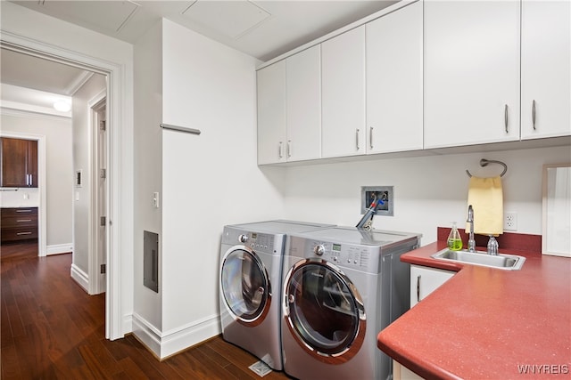 clothes washing area featuring cabinets, sink, ornamental molding, washer and clothes dryer, and dark hardwood / wood-style floors