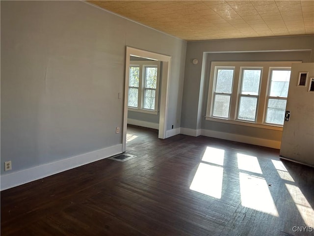 unfurnished room featuring dark wood-type flooring and a wealth of natural light