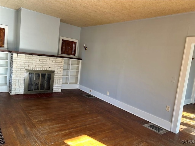 unfurnished living room with a textured ceiling, a brick fireplace, and dark wood-type flooring