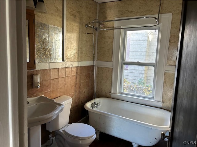 bathroom with a bath, tile walls, and toilet