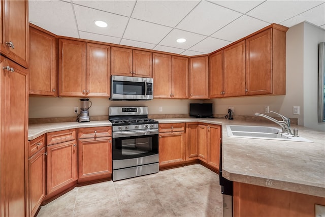 kitchen with light tile patterned floors, a paneled ceiling, sink, and appliances with stainless steel finishes