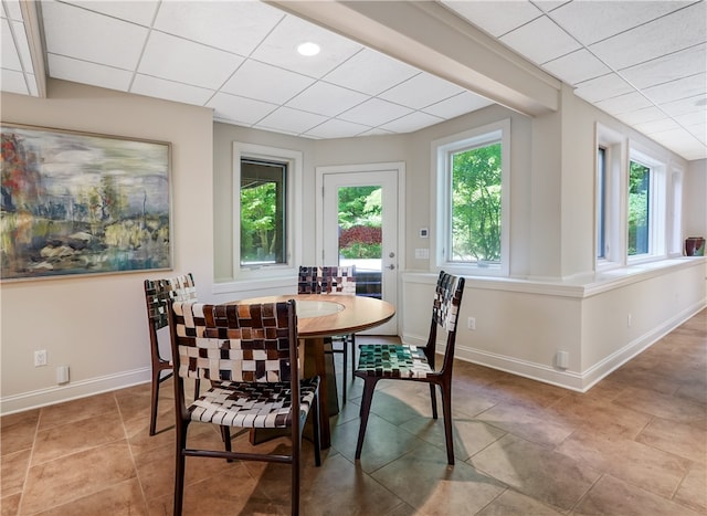 dining space featuring a wealth of natural light, a paneled ceiling, and light tile patterned floors