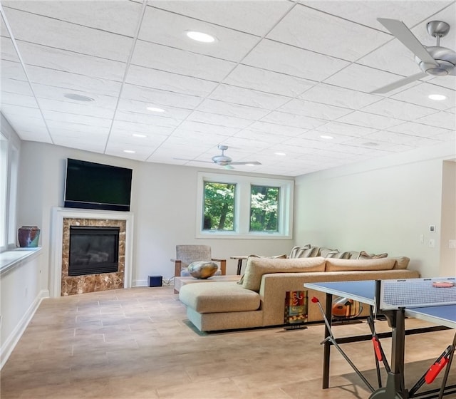 living room with a drop ceiling, a fireplace, and ceiling fan