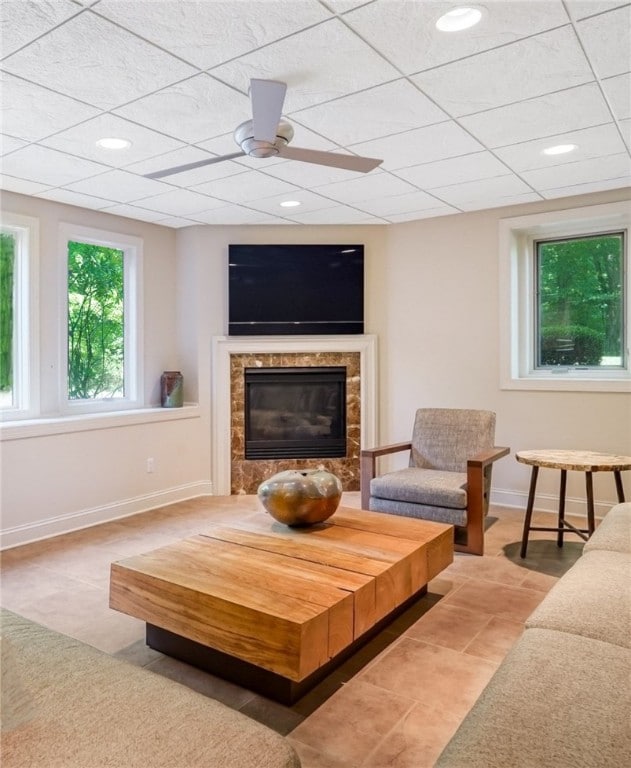 living room featuring a drop ceiling, ceiling fan, and light tile patterned floors