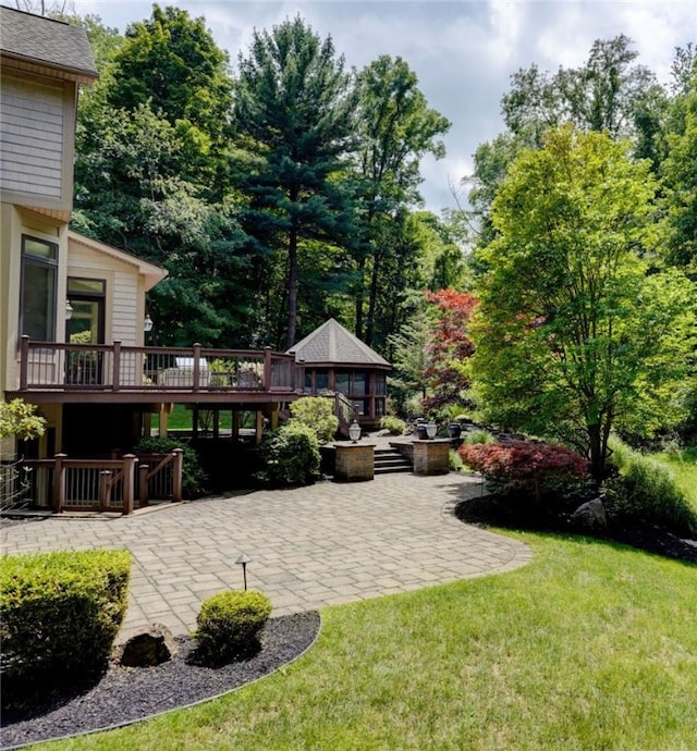 view of yard featuring a wooden deck and a patio