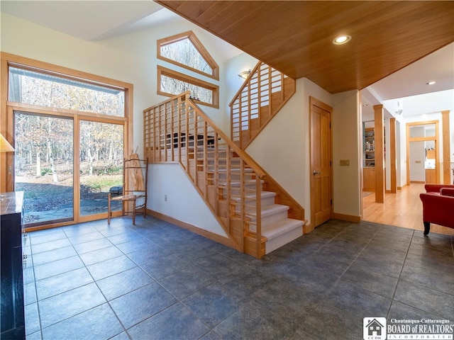 stairway with wooden ceiling, tile patterned floors, and vaulted ceiling