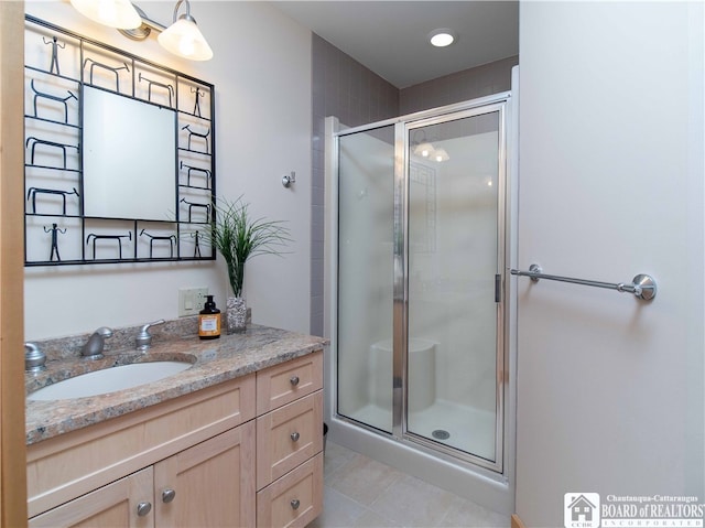 bathroom with a shower with door, vanity, and tile patterned flooring