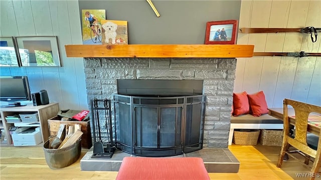 details with a stone fireplace, wood finished floors, and wooden walls